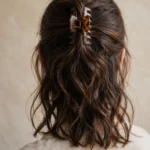 Back view of medium length hair held up in a claw clip hairstyle with soft waves below the clip
