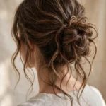Back view of long wavy hair in a loose relaxed messy bun with soft face-framing strands